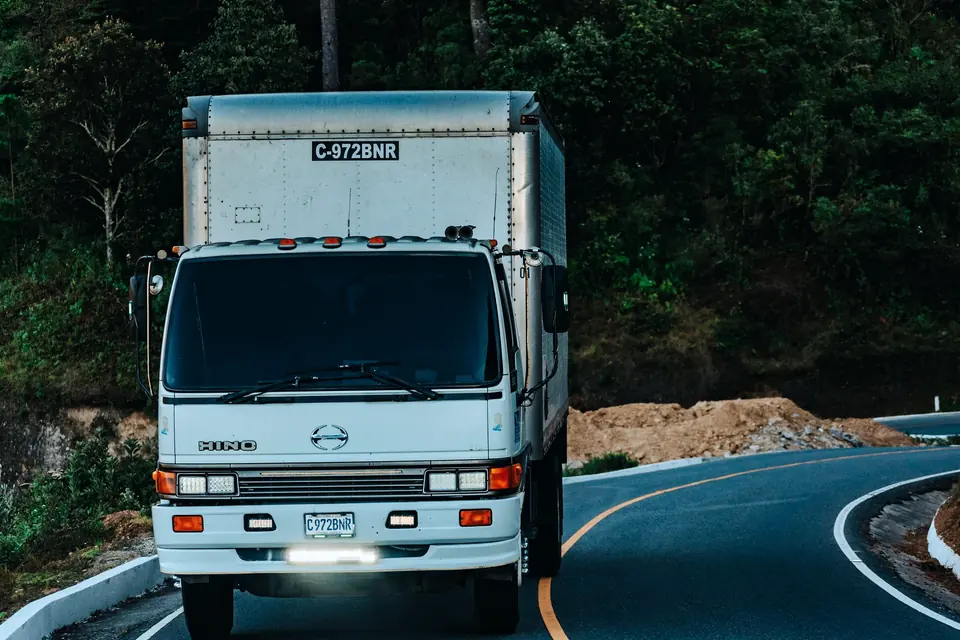 White box truck driving on a winding forest road