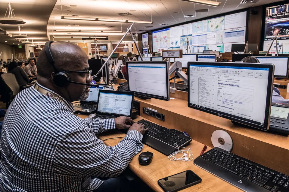 Dispatcher wearing a headset working across several monitors