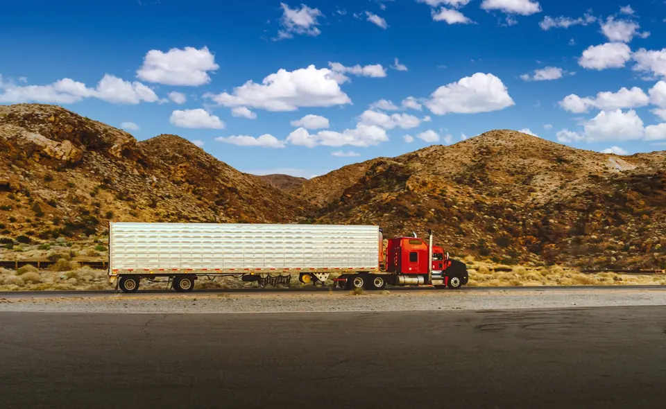 Red semi truck pulling a refrigerated trailer through the Nevada desert
